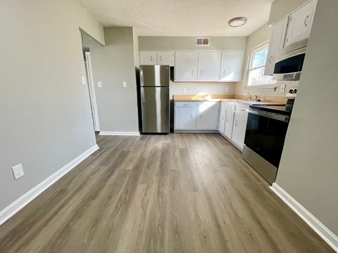 A kitchen with a refrigerator, oven, and microwave.
