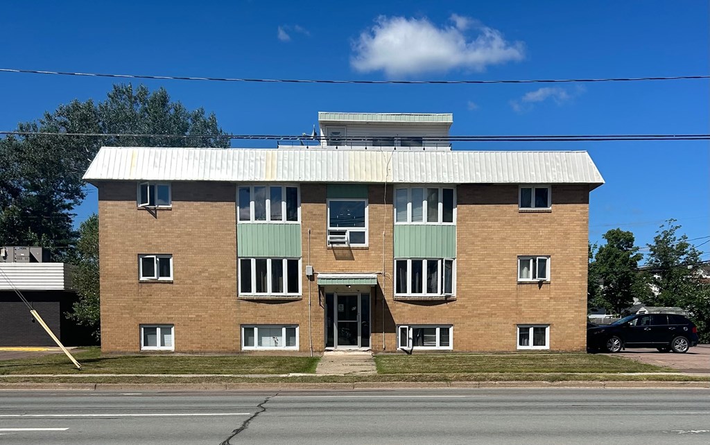 A large brick building with a green awning and a white roof.