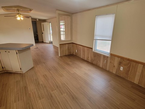 A room with wooden floors and a window with blinds.