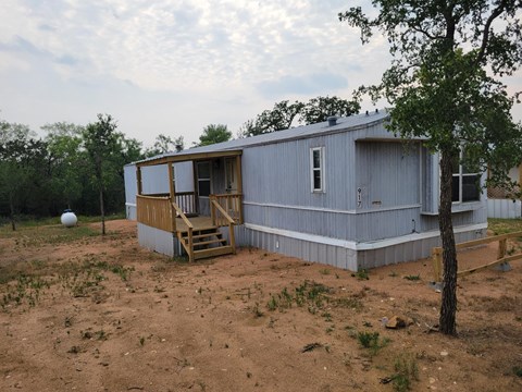 A house with a porch and a tree in front of it.