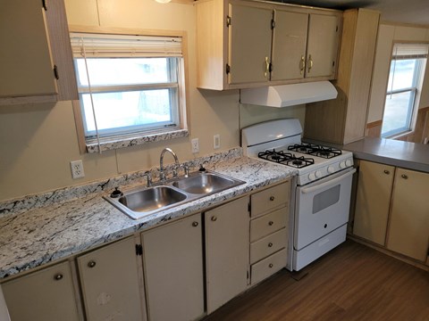 A kitchen with a white stove and sink.