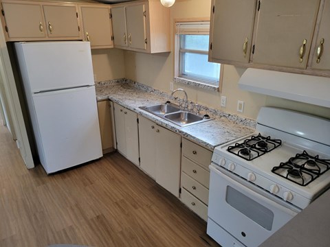 A kitchen with a white fridge, stove, and cabinets.