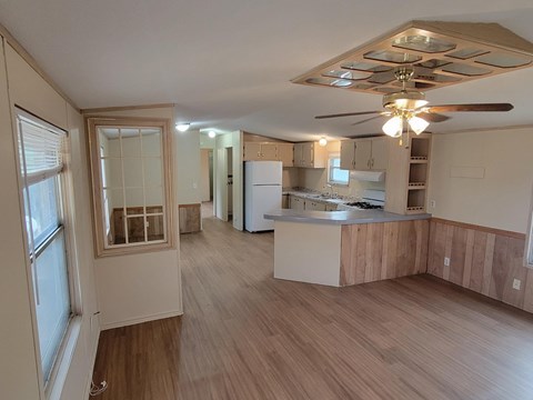 A kitchen with a refrigerator, cabinets, and a ceiling fan.