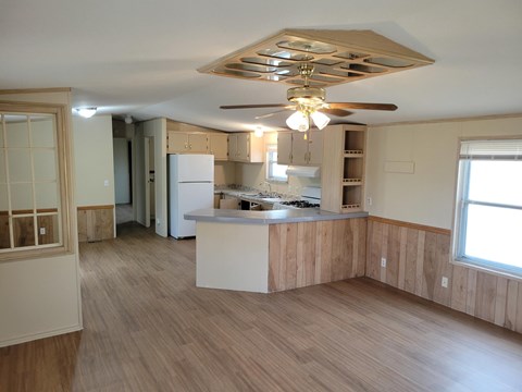 A kitchen with wooden floors and a ceiling fan.