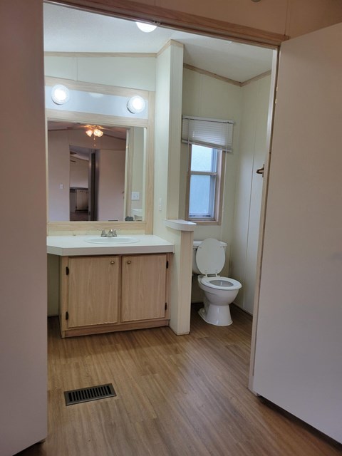 A bathroom with a toilet, sink, and mirror.
