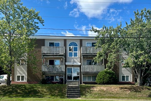 A large apartment building with a balcony and stairs leading to the entrance.