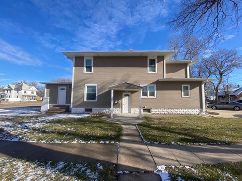 A house with a grey facade stands in a residential area.