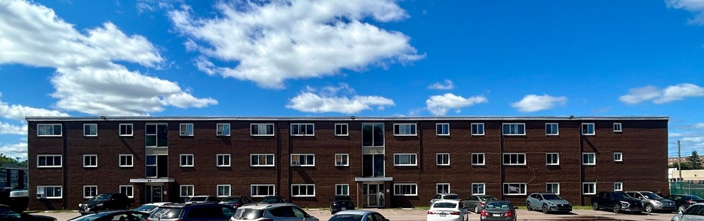 A large brick building with a parking lot in front.