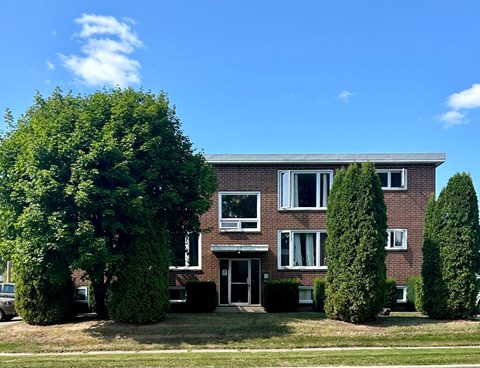 A red brick building with a green lawn in front.