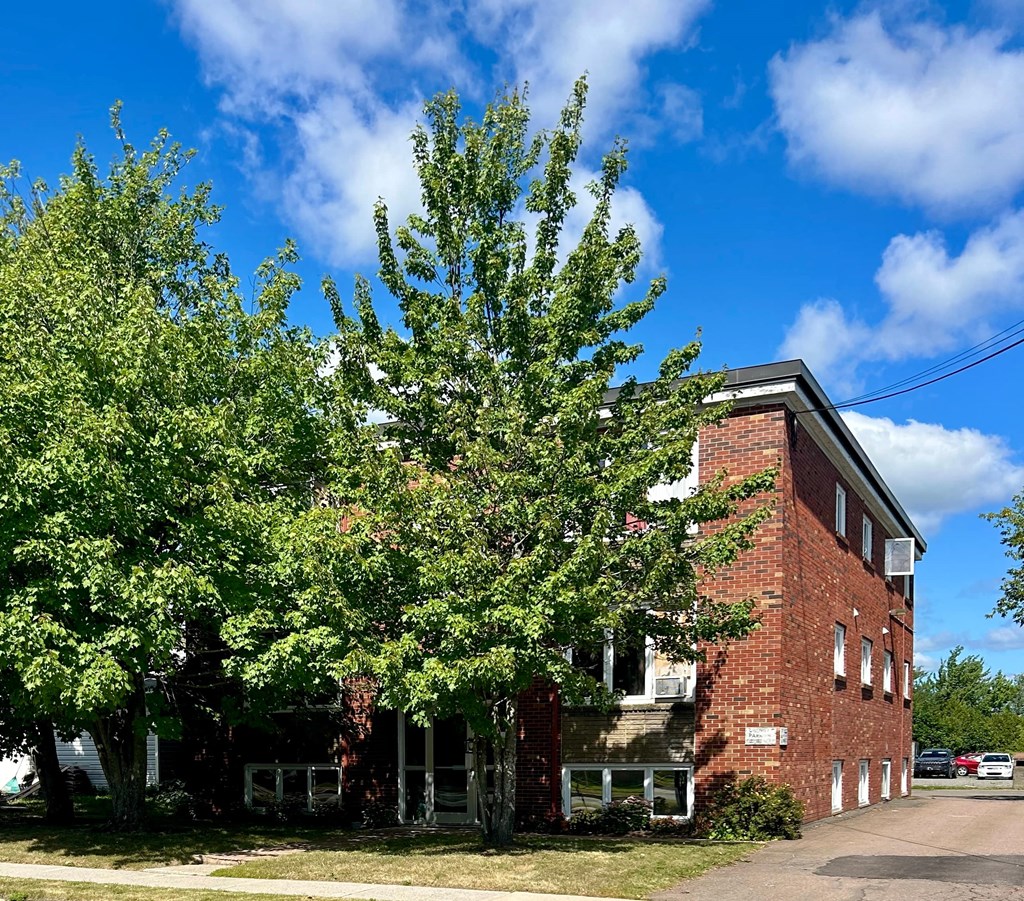 A red brick building with a tree in front of it.