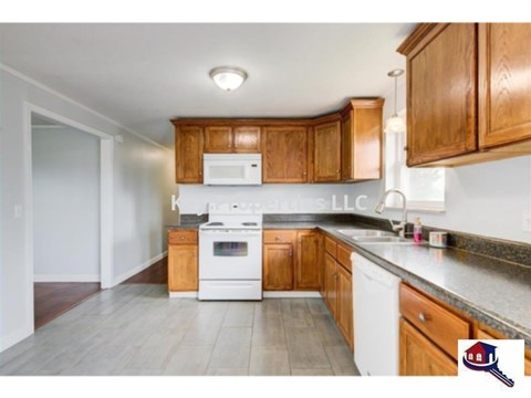 A kitchen with wooden cabinets and a white stove top oven.