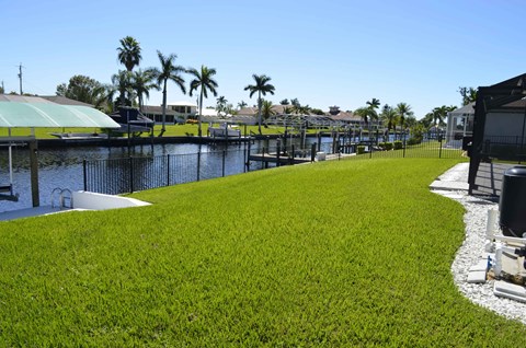 A grassy area with a fence and a body of water.