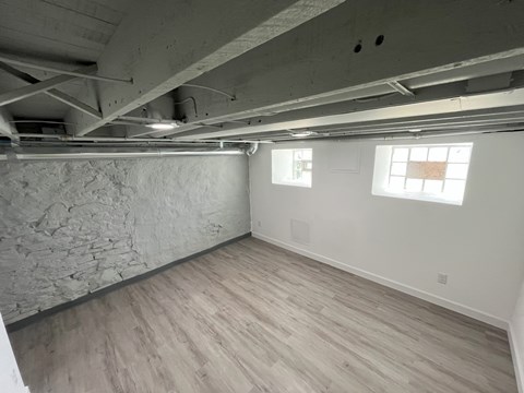A room with wooden flooring and a stone wall.