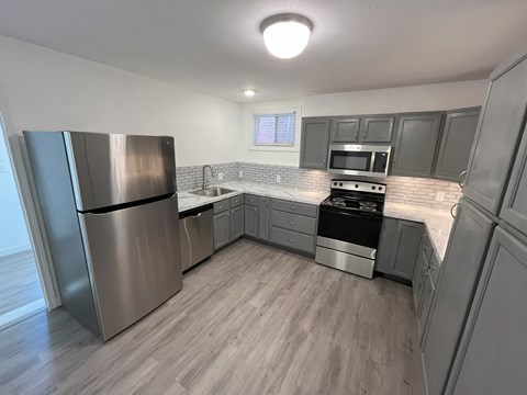 A kitchen with a stainless steel refrigerator, microwave, and oven.