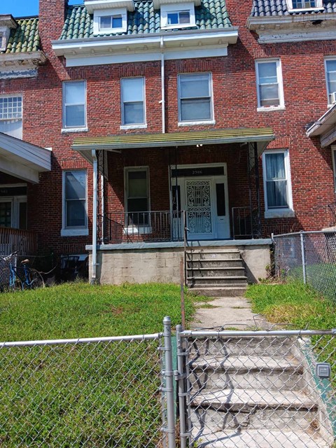 A red brick house with a white door and a small porch.
