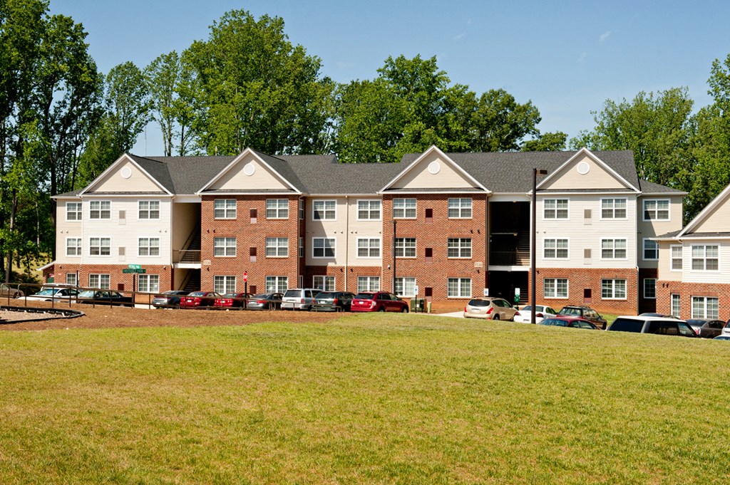 A large red brick building with a parking lot in front.