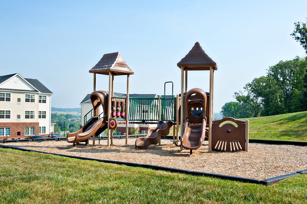 A playground with a slide, swings, and a seesaw.