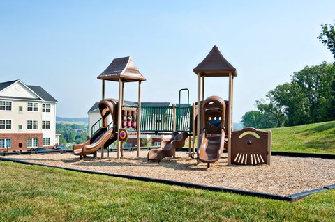 A playground with a slide, swings, and a seesaw.