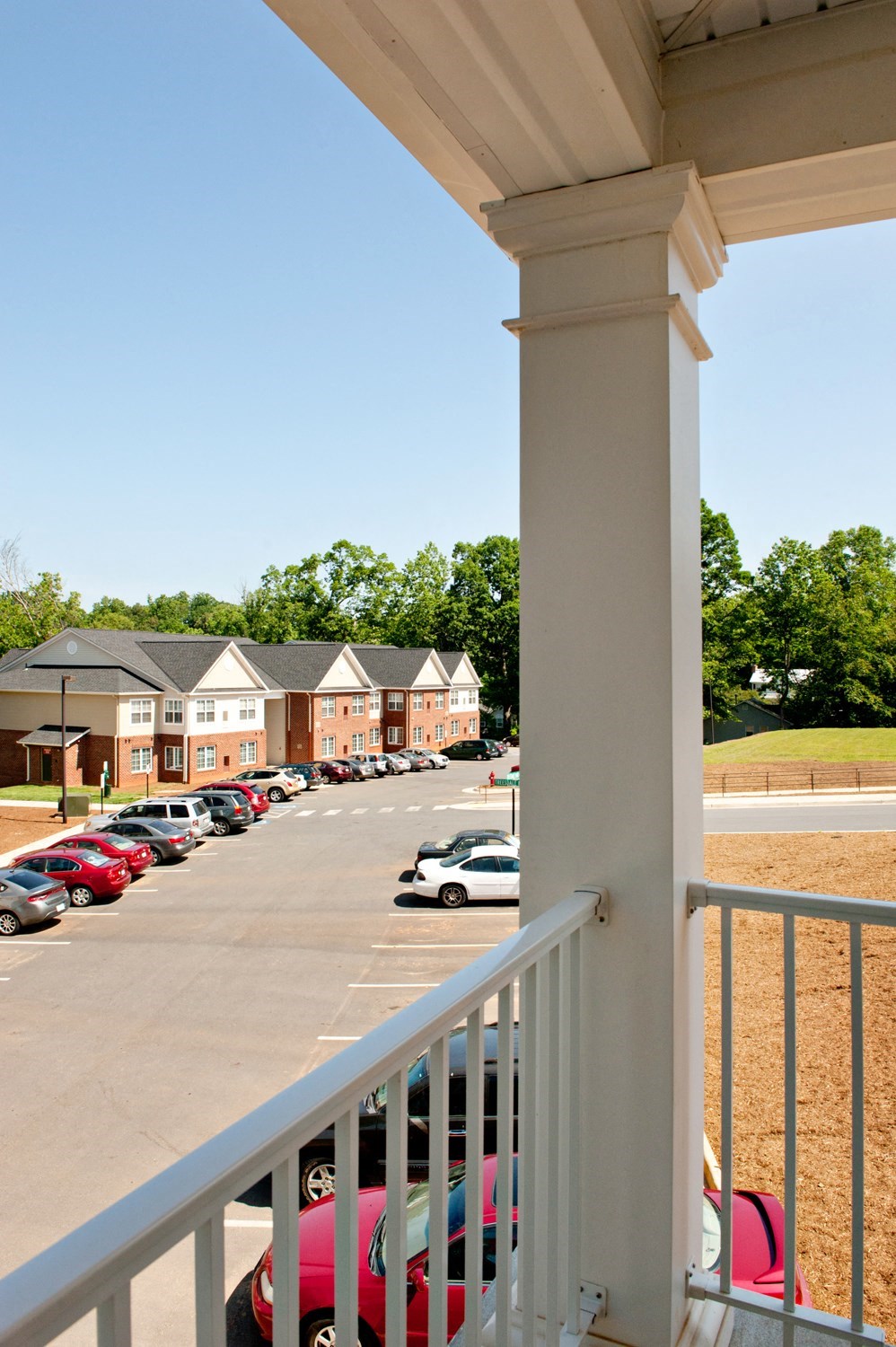 A white railing overlooks a parking lot.