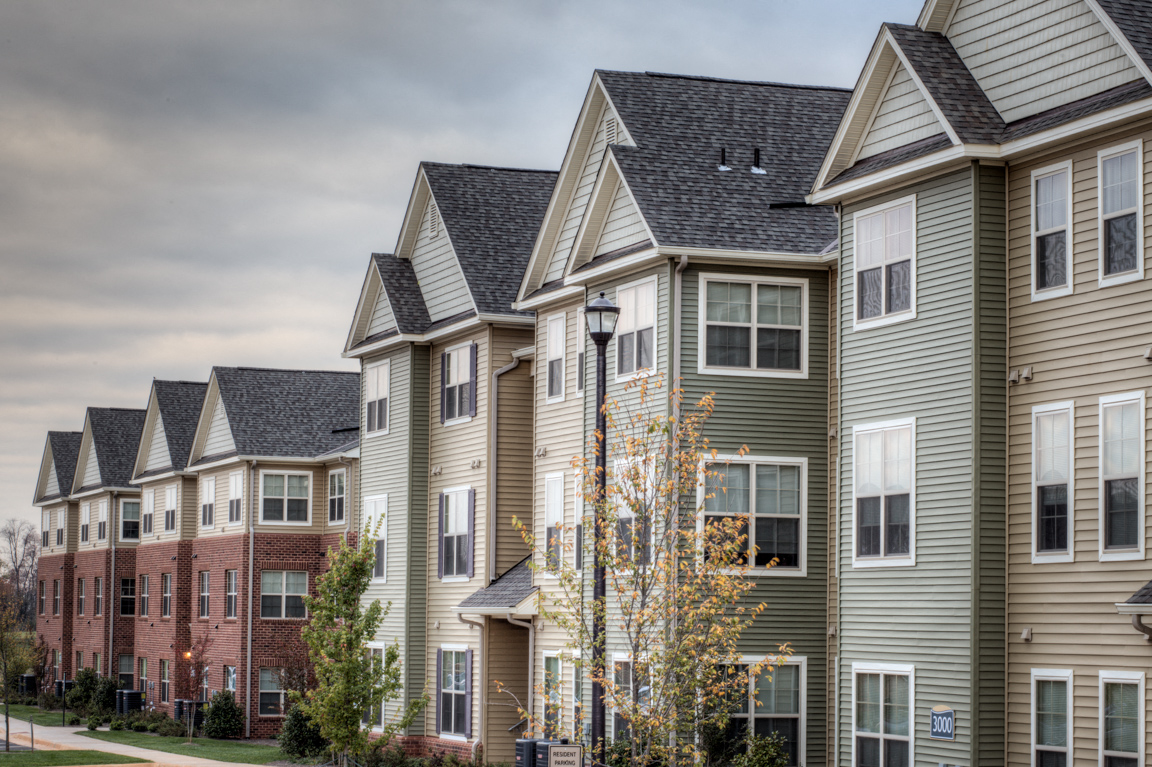 a row of town houses on a street with a cloudy sky