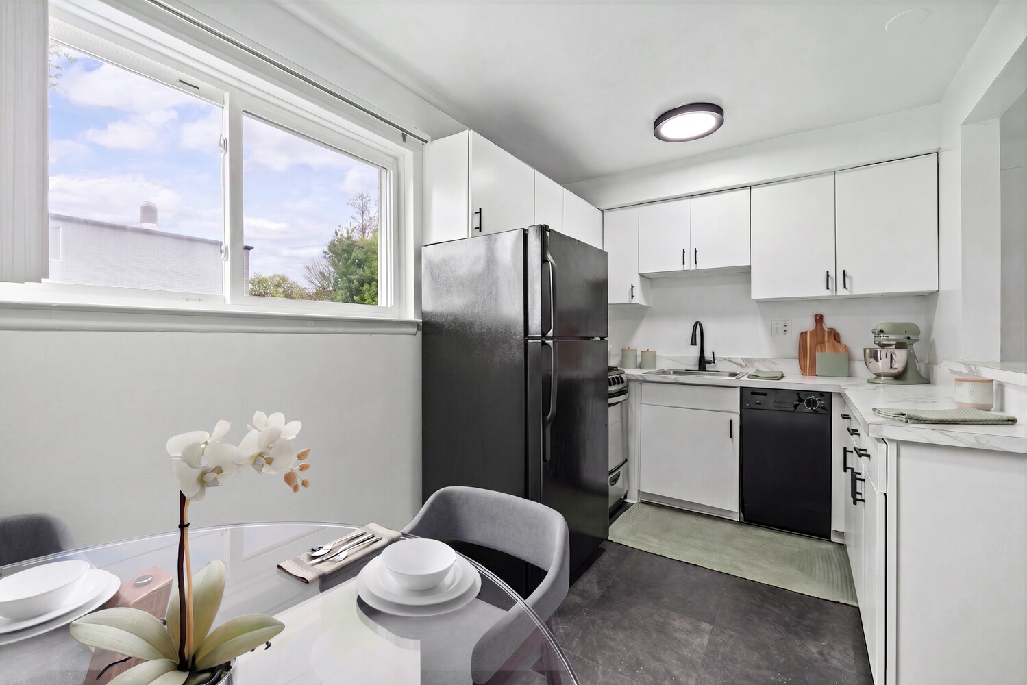 A kitchen with a table and chairs in front of it.