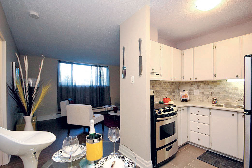 A kitchen with a table set for two with orange juice and two glasses.