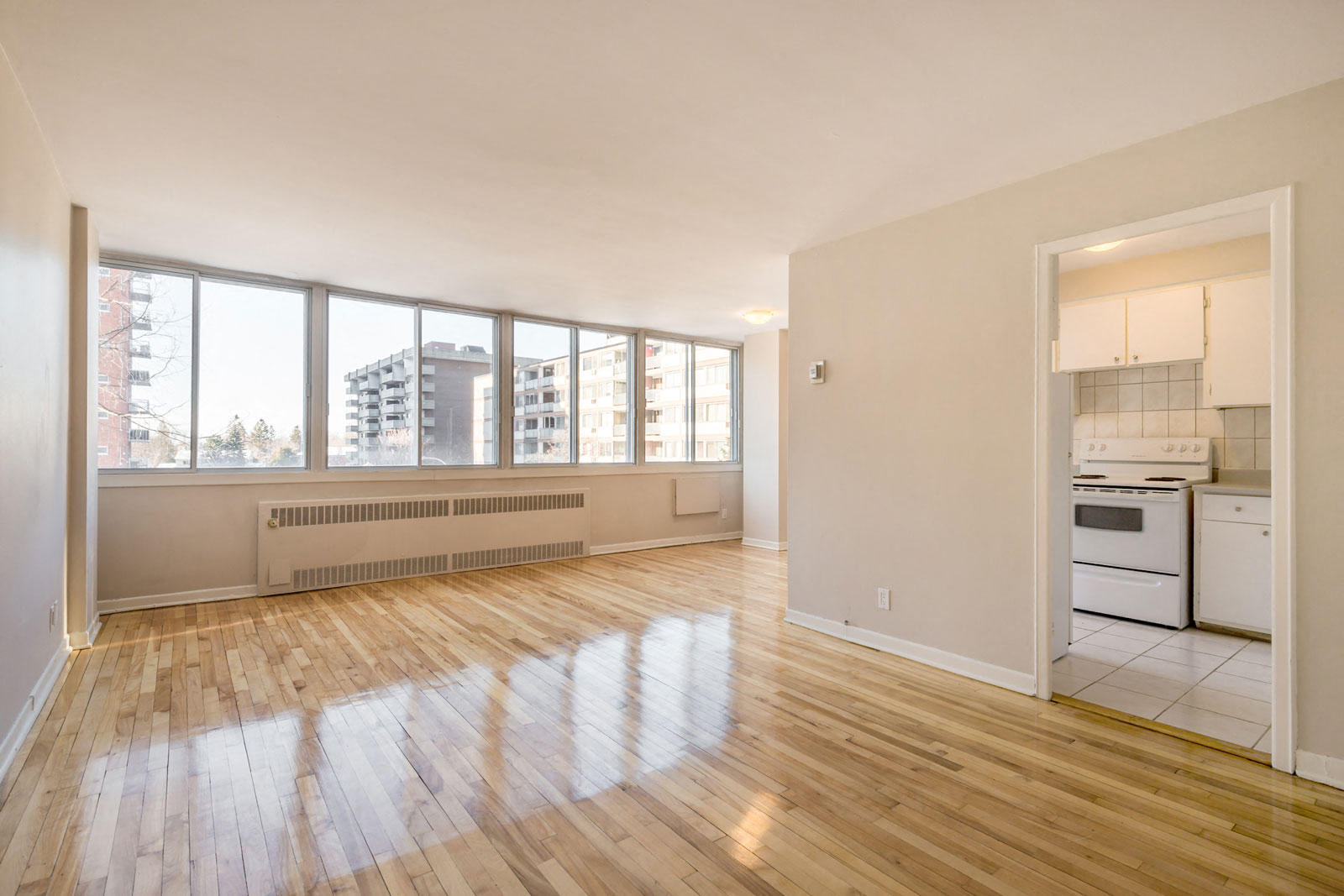 A spacious room with wooden floors and a kitchen area.