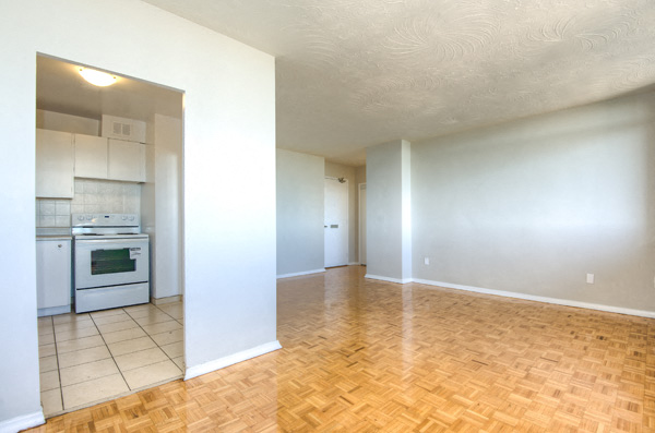 A kitchen with white cabinets and a stove top oven is visible through a doorway.