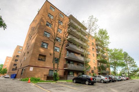 A large brick apartment building with cars parked in front.