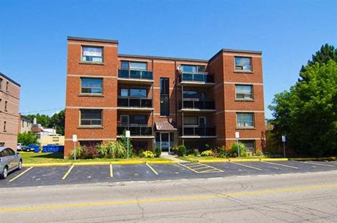 A multi-story brick building with a parking lot in front.