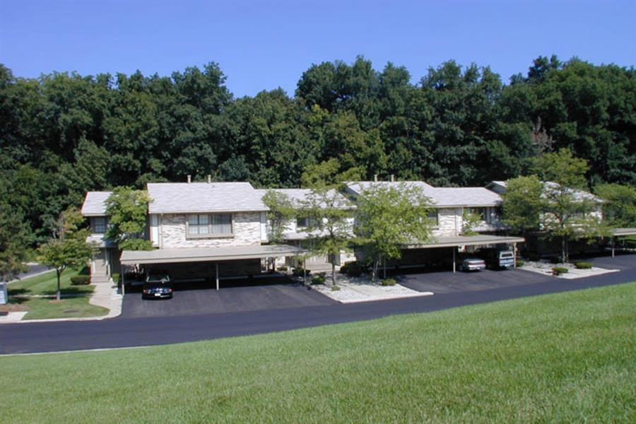 a white house with a parking lot and trees