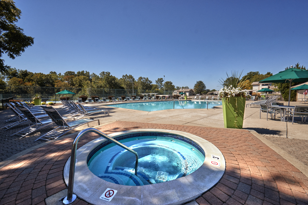 a spa with a hot tub and chairs around a pool