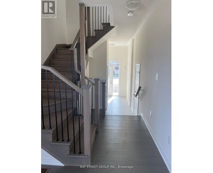 A hallway with a staircase and a door at the end.