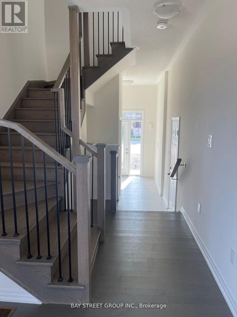 A hallway with a staircase and a door at the end.