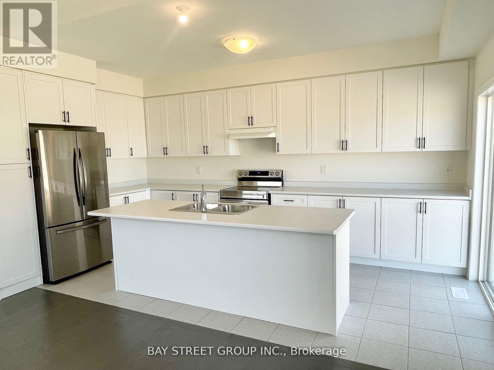 A kitchen with white cabinets and a stainless steel refrigerator.