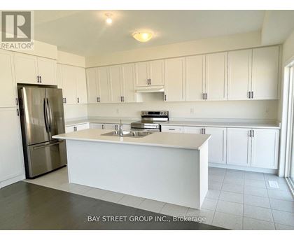 A kitchen with white cabinets and a stainless steel refrigerator.