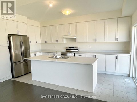 A kitchen with white cabinets and a stainless steel refrigerator.