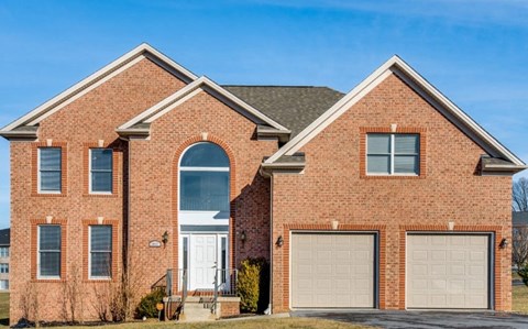 A red brick house with a white door and two garage doors.