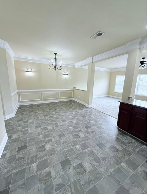 A spacious room with a checkered tile floor and a chandelier.