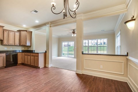 A large open kitchen and living room with wood floors and a chandelier.