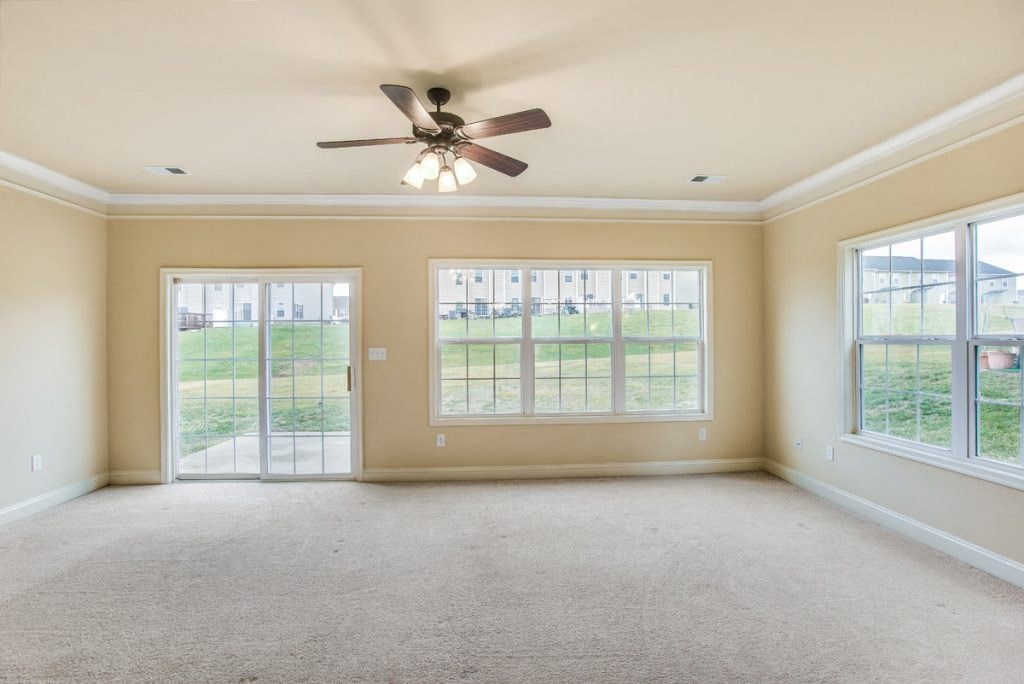 A spacious room with a ceiling fan and large windows.