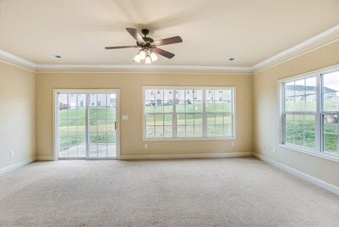 A spacious room with a ceiling fan and large windows.