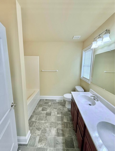 A bathroom with a toilet, sink, and mirror.
