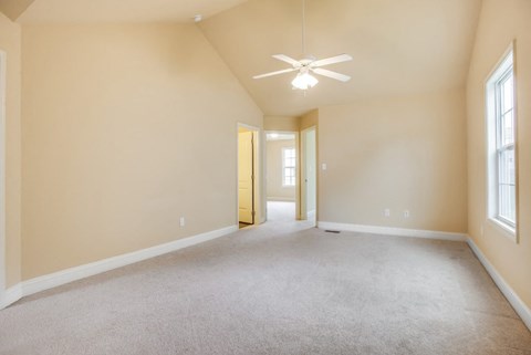 Empty room with a ceiling fan and carpeted floor.