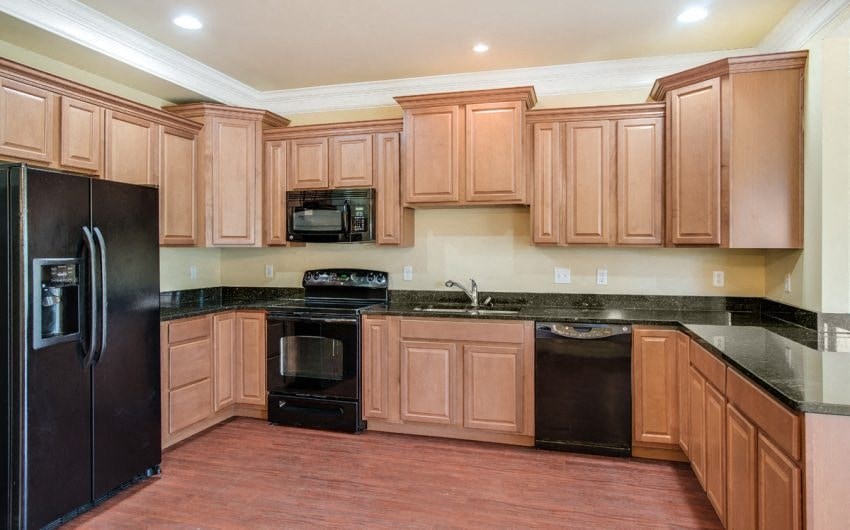 A kitchen with wooden cabinets and black appliances.