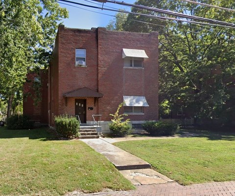 A red brick house with a white window and a brown door.