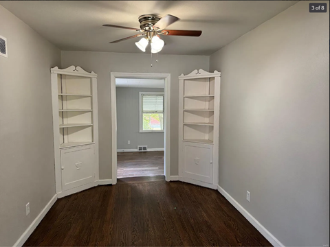 A room with a ceiling fan and two open doors.