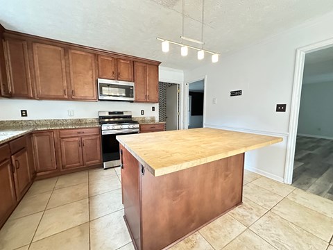 A kitchen with brown cabinets and a wooden island.
