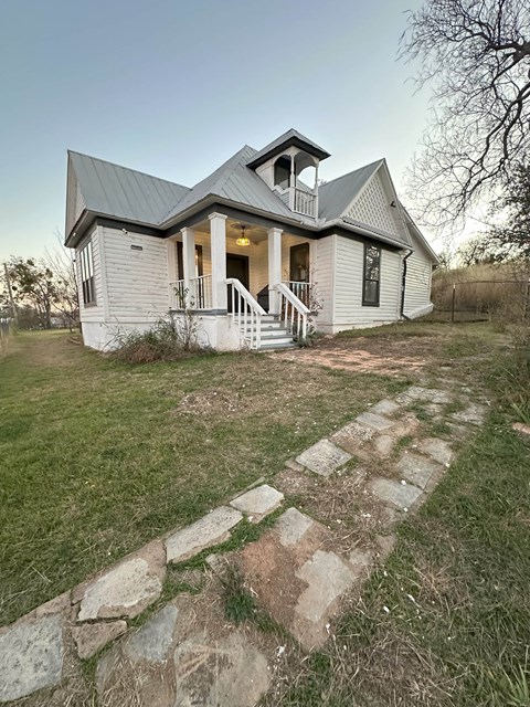 A white house with a grey roof and a stone pathway leading to the front door.