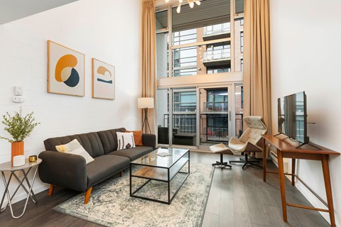 A living room with a black couch, a coffee table, and a flat screen TV.